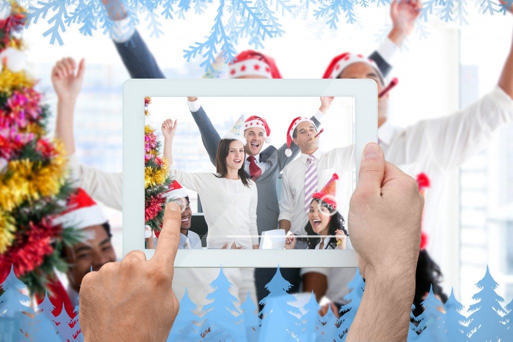 Hand holding tablet taking picture of people celebrating christmas