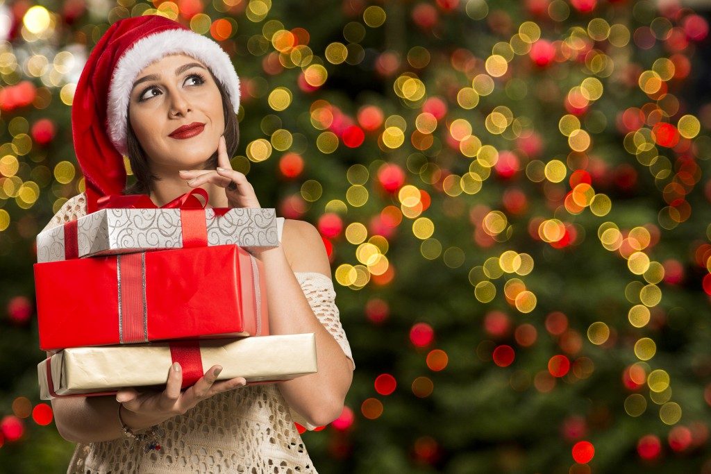 Woman with santa claus hat holding gifts