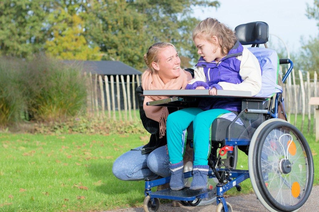 Disabled child in wheelchair being accompanied outdoors