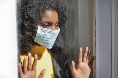 woman wearing mask looking out the window